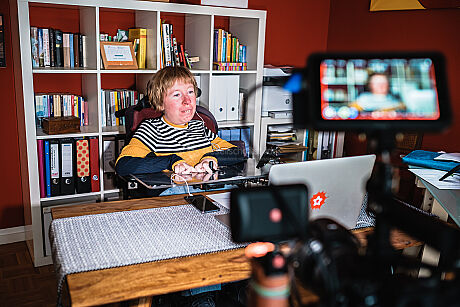 Anne Gersdorff sitzt vor einem Notebook in ihrem Büro. Eine Kamera filmt sie ab.